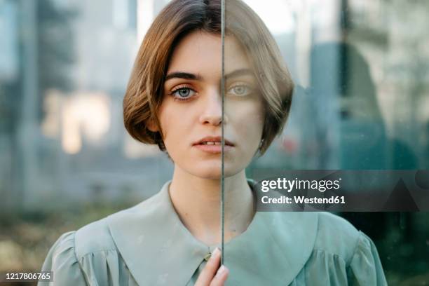 portrait of woman with half of her face behind a glass - introvert stock-fotos und bilder