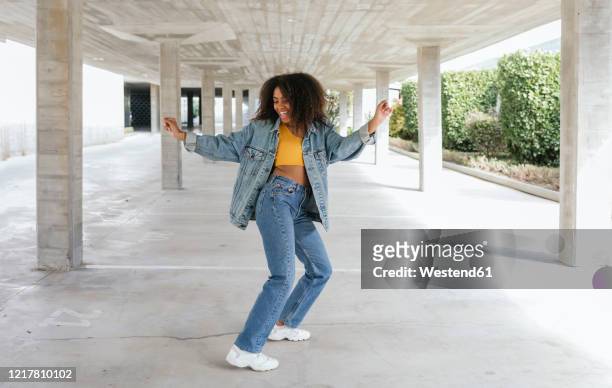 smiling woman dancing in an empty parking - jeans foto e immagini stock