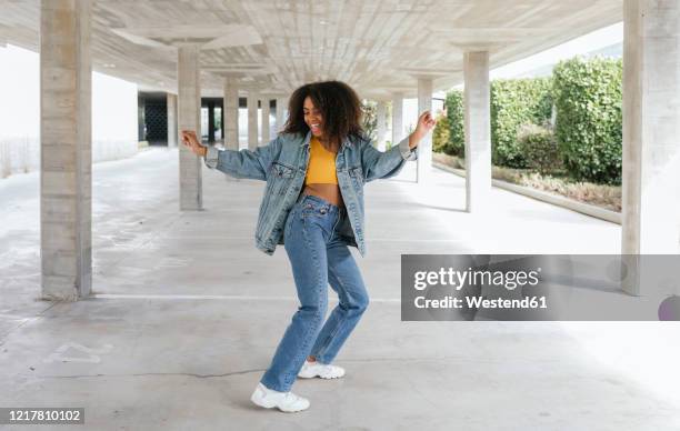 smiling woman dancing in an empty parking - jeans woman stock pictures, royalty-free photos & images