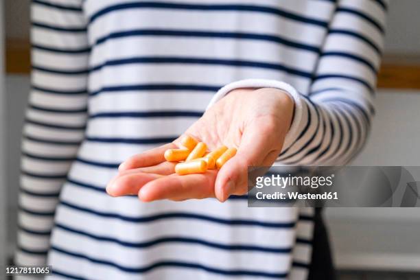 close-up of woman holding pills - hand holding several pills photos et images de collection