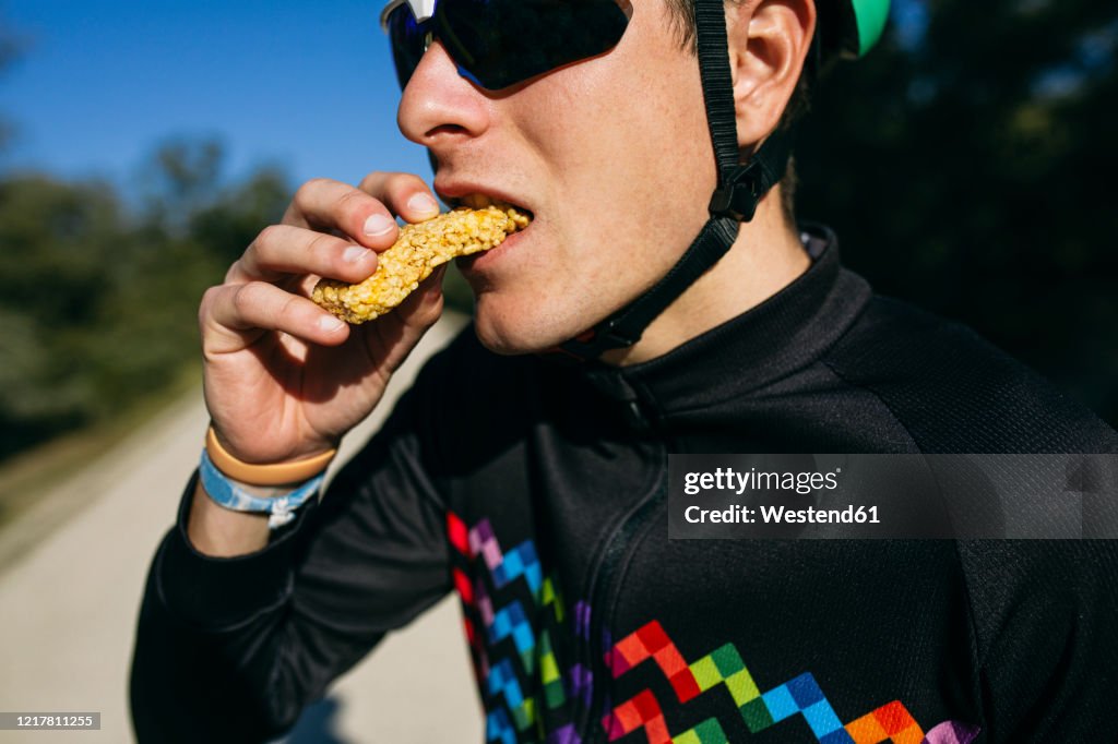 Portrait of cyclist eating a snack during a break on a sunny day