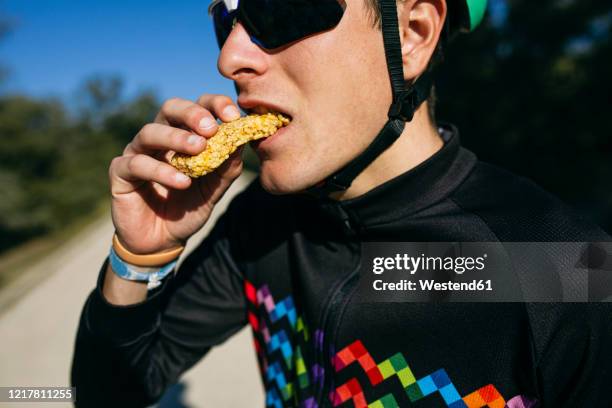 portrait of cyclist eating a snack during a break on a sunny day - fietsers stockfoto's en -beelden