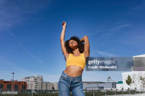 smiling young woman dancing with eyes closed - bauchfreies oberteil stock-fotos und bilder