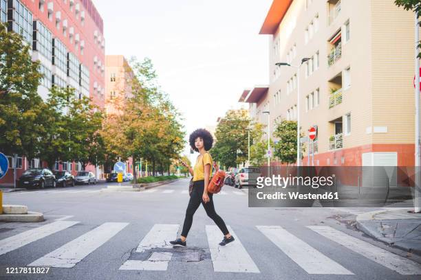 young woman with afro hairdo walking in the city - crossing stock pictures, royalty-free photos & images