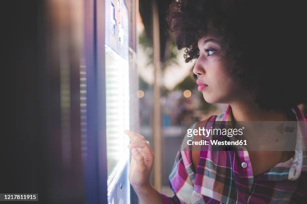 young woman with afro hairdo using touchscreen vending machine in the city - vending machine stock pictures, royalty-free photos & images