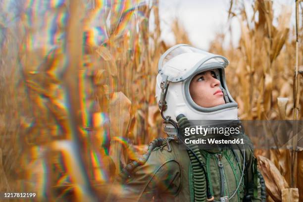 young spaceman standing in wilted corn field - forschung teenager stock-fotos und bilder