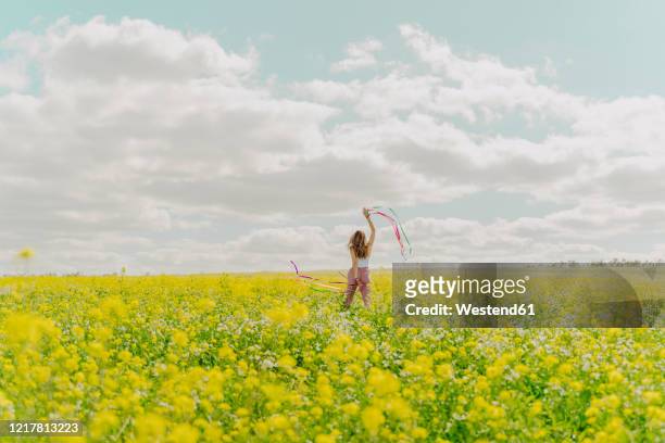 young woman with colourful ribbons in a flower meadow in spring - ribbon dance stock pictures, royalty-free photos & images