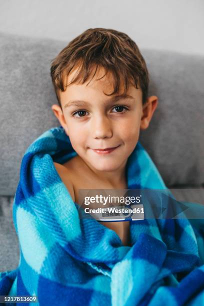 portrait of sick boy sitting on couch with digital thermometer - boy armpit stock-fotos und bilder