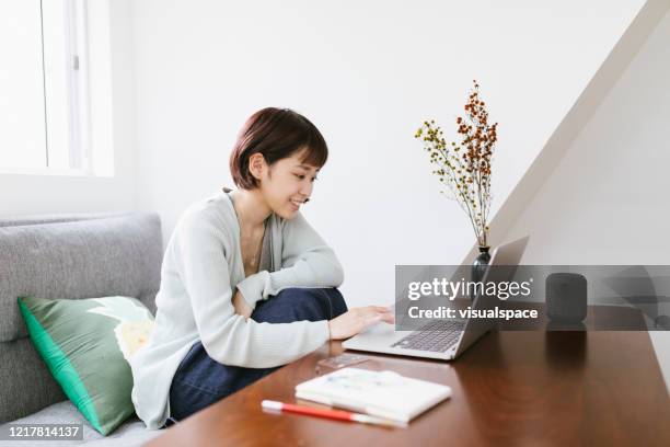 リモートワーキング - ホームオフィスで働く若いアジア人女性 - notebook ストックフォトと画像
