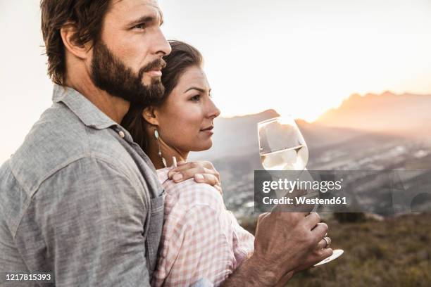affectionate couple having a glass of white wine in the countryside at sunset - franschhoek stock-fotos und bilder