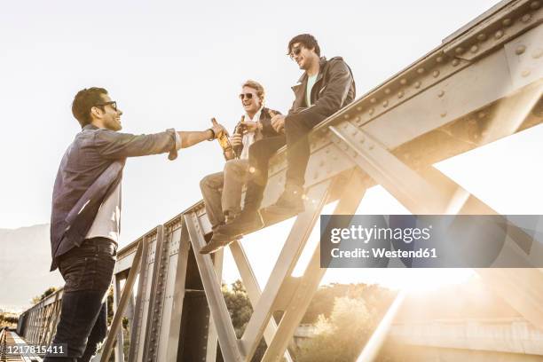 three men drinking beer on an old railway bridge - railway bridge stock-fotos und bilder