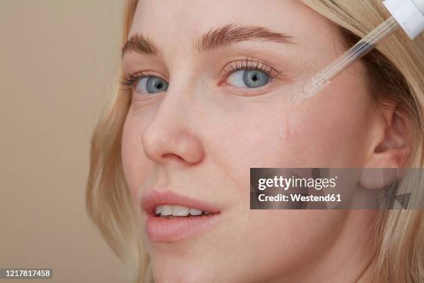 portrait of young woman applying skin care - augen schönheit creme stock-fotos und bilder