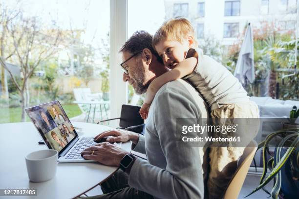 little boy hugging father from behind, while working from home - working from home stock-fotos und bilder