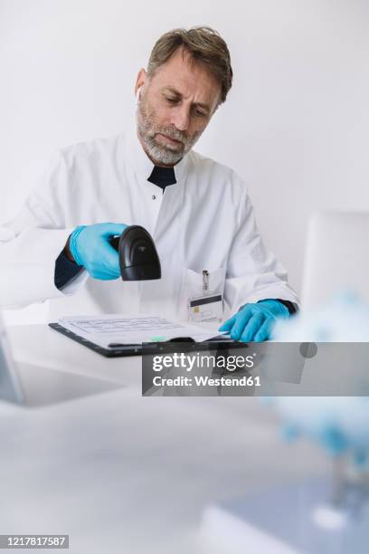 scientist scanning forms at desk - digitalisation photos et images de collection