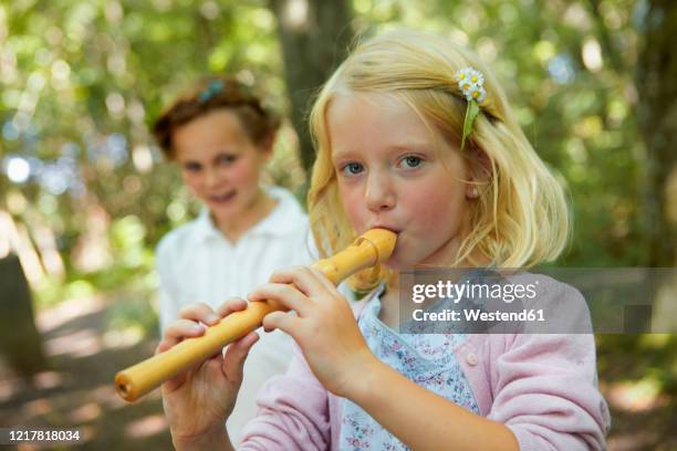 portrait of girl playing recorder in forest - flöte stock-fotos und bilder