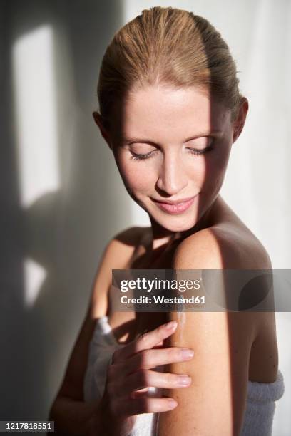 portrait of beautiful woman applying skin cream on her arm - verwöhnen stock-fotos und bilder