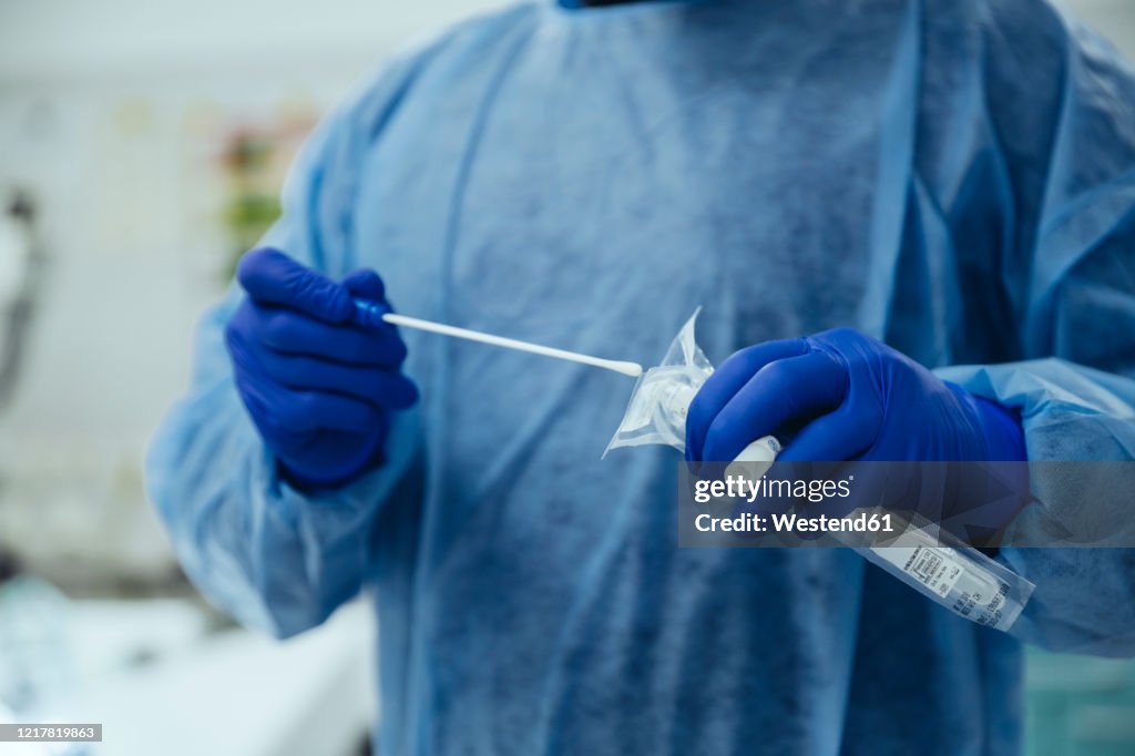 Close-up of emergeny doctor putting a swab into a tube in hospital