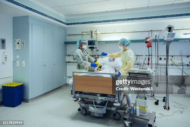 doctors caring for patient in emergency care unit of a hospital taking blood sample - intensivstation stock-fotos und bilder