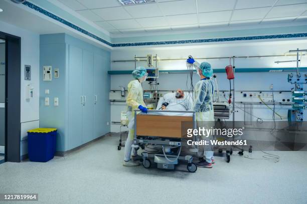 doctors caring for patient in emergency care unit of a hospital with respiratory equipment - intensieve zorg stockfoto's en -beelden