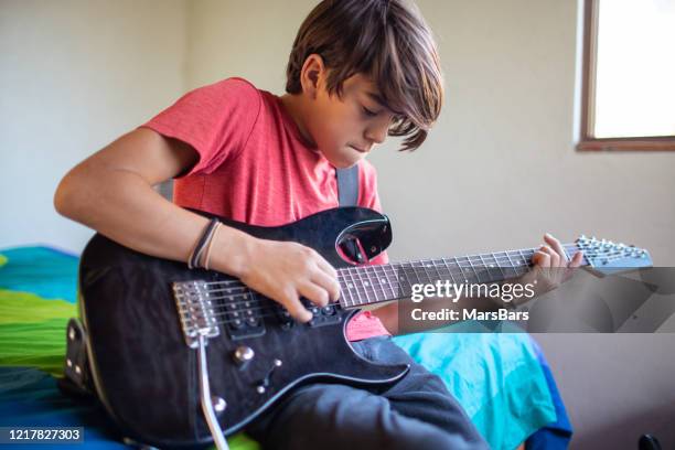 latinx pre-adolescent child learning to play electric guitar at home - electric guitar stock pictures, royalty-free photos & images