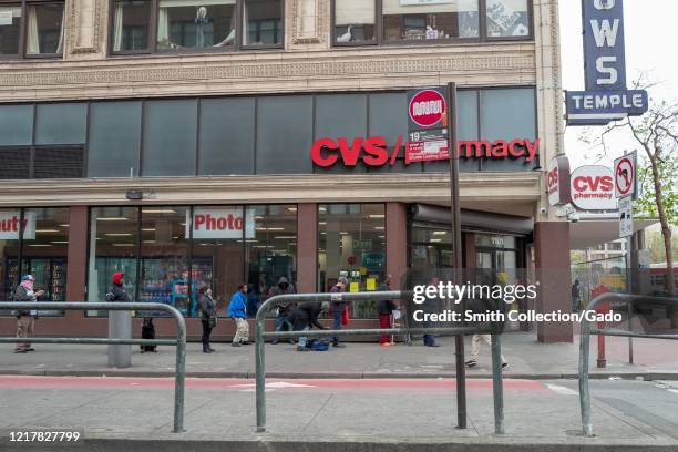 People wait in line while observing social distancing rules at a CVS Pharmacy in the Tenderloin neighborhood of San Francisco, California during an...