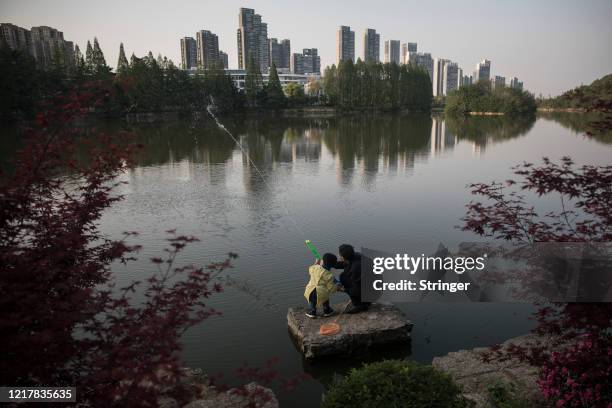 April 09: A boy and him grandpa play water pistol at Eastlake park on April 9,2020 in Wuhan, Hubei Province, China.The government started lifting...