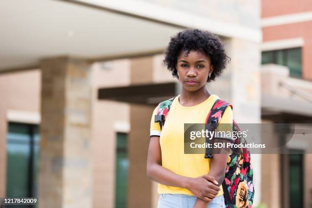 boos, misschien bezorgd, tween meisje voor schoolgebouw - alleen één meisje stockfoto's en -beelden