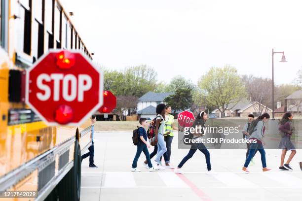 kreuzungsschutz mit stoppschild hilft kindern beim überqueren der straße - cross road children stock-fotos und bilder