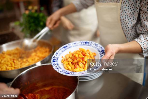 chef donna che serve pasta in un piatto - cavatelli foto e immagini stock