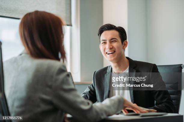 aziatische chinese glimlachende jonge zakenman die bespreking in de vergaderingsruimte heeft - colleagues in discussion in office conference room stockfoto's en -beelden