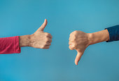 Two people making hand sign thumbs up and thumbs down, yes or no, like or dislike concept.