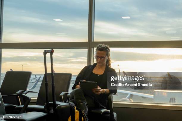 de vrouw wacht in luchthaven en controleert e-mail bij dageraad - woman blond looking left window stockfoto's en -beelden
