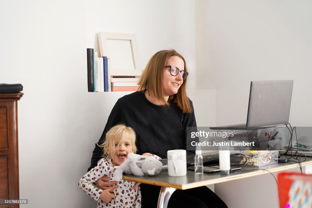 Mom working from home fending off her child while on a conference call