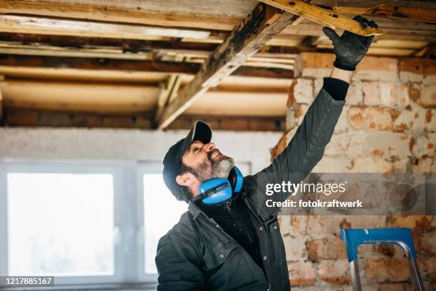 männlicher arbeiter repariert dachbalken zu hause - wiederbelebung stock-fotos und bilder