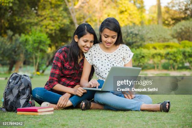 students studying outdoors on the grass stock photo - indian college girls stock pictures, royalty-free photos & images