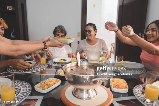 familie mittagessen am esstisch serviert mit feijoada, typisch brasilianischen schwarzen bohnen eintopf - brazilian feijoada dish stock-fotos und bilder