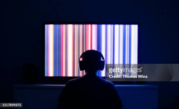 person sitting in front of a tv screen with headphones - saturated color stock-fotos und bilder