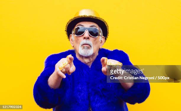 portrait of grandfather pointing at camera on yellow background - dj portrait stock pictures, royalty-free photos & images