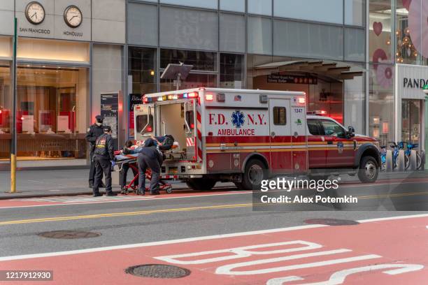 paramedics loading a patient into the ambulance on 42 street in midtown manhattan. - alex potemkin coronavirus stock pictures, royalty-free photos & images