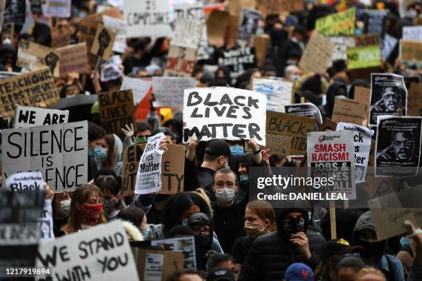 Protesters hold placards as they attend a demonstration in Parliament Square in central London on June 6 to show solidarity with the Black Lives...