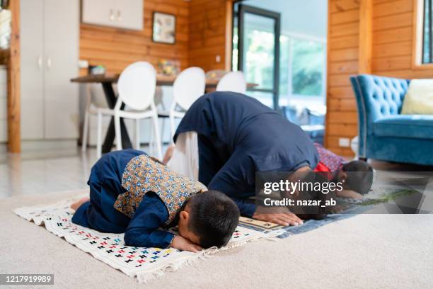 father with two kids prostrating during prayer. - muslim prayer stock pictures, royalty-free photos & images