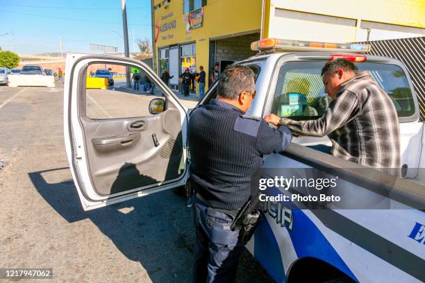 ein mexikanischer polizist mit einem migranten nahe der mexikanisch-amerikanischen grenze in tijuana - border patrol monitors california mexico border stock-fotos und bilder