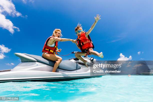 feliz madre soltera e hijo divirtiéndose en jet boat en el mar. - jet boat fotografías e imágenes de stock