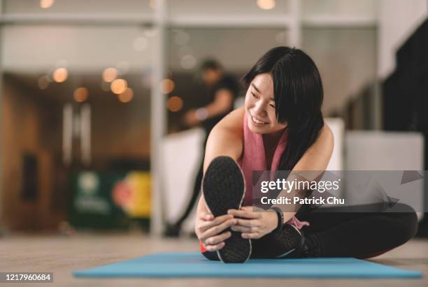 junge asiatische chinesische frauen tun stretching-übung im fitnessstudio - zehenspitzen berühren stock-fotos und bilder