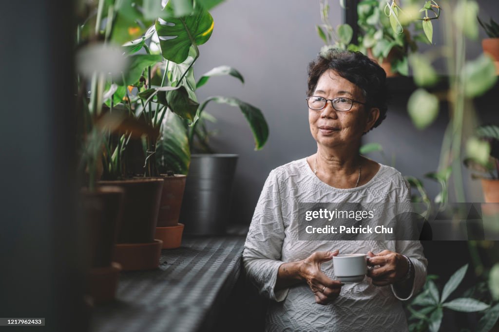 Friedliche senior asiatische chinesische Frau beim Kaffee zu Hause chillen