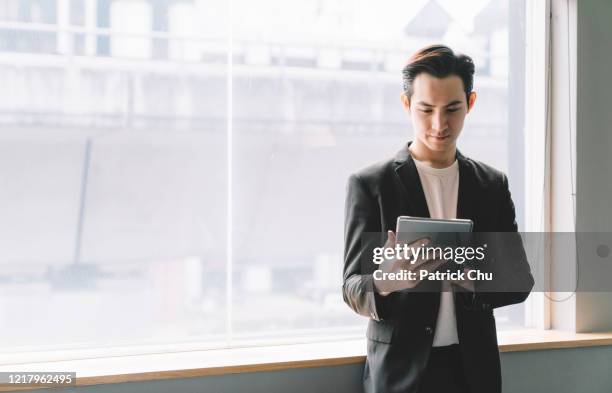 giovane uomo d'affari asiatico cinese utilizzando tablet - man suit using phone tablet foto e immagini stock