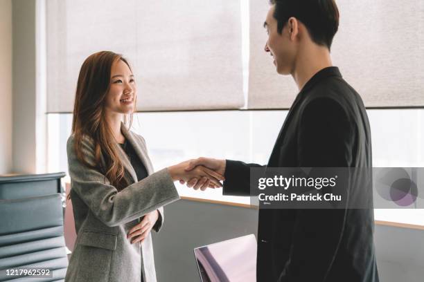 aziatische chinese zakenman en onderneemster die handen bij bureau schudden - asian shaking hands stockfoto's en -beelden