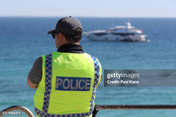 Police officer keeps watch on crowd numbers at Cottesloe Beach on April 10, 2020 in Perth, Australia. Australians have been urged to avoid all...