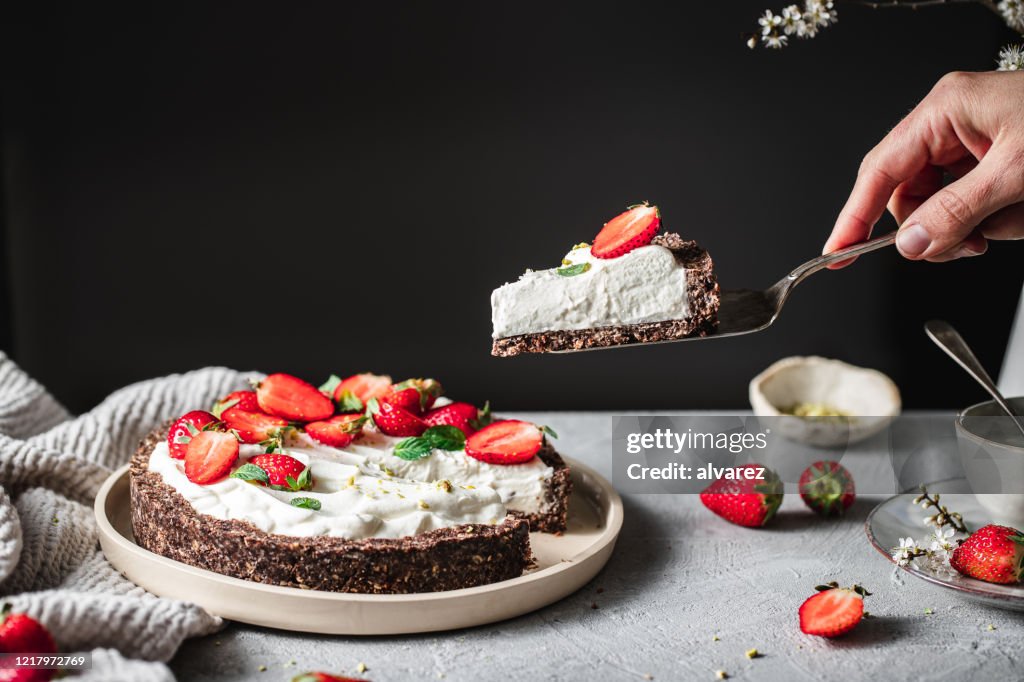 Frau nimmt eine Portion eines Joghurt Erdbeerkuchen