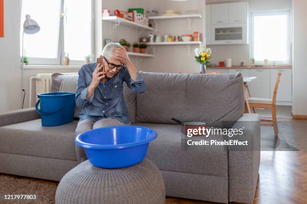 angry senior women talking on smartphone because of roof leaking - leaky roof stock pictures, royalty-free photos & images